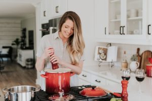 Woman cooking in a white kitchen with red kitchen tools