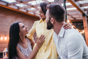 Young couple smiling outside with their kid