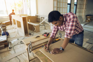 Carpenter drawing lines on wood at a construction site