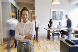 Business woman smiling at camera with blur figures behind