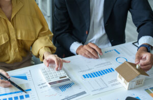 Two people sitting at a desk with documents about housing and mortgages.