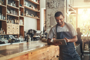 Happy male owner of a cafe using digital tablet.