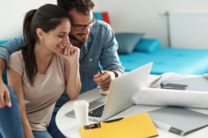 Happy couple sitting at desk with papers and laptop